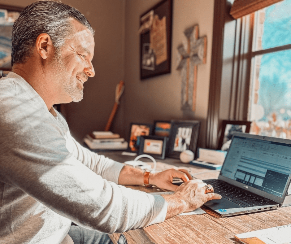 Todd A. Tressler working at his desk on his laptop with sunlight coming through the window