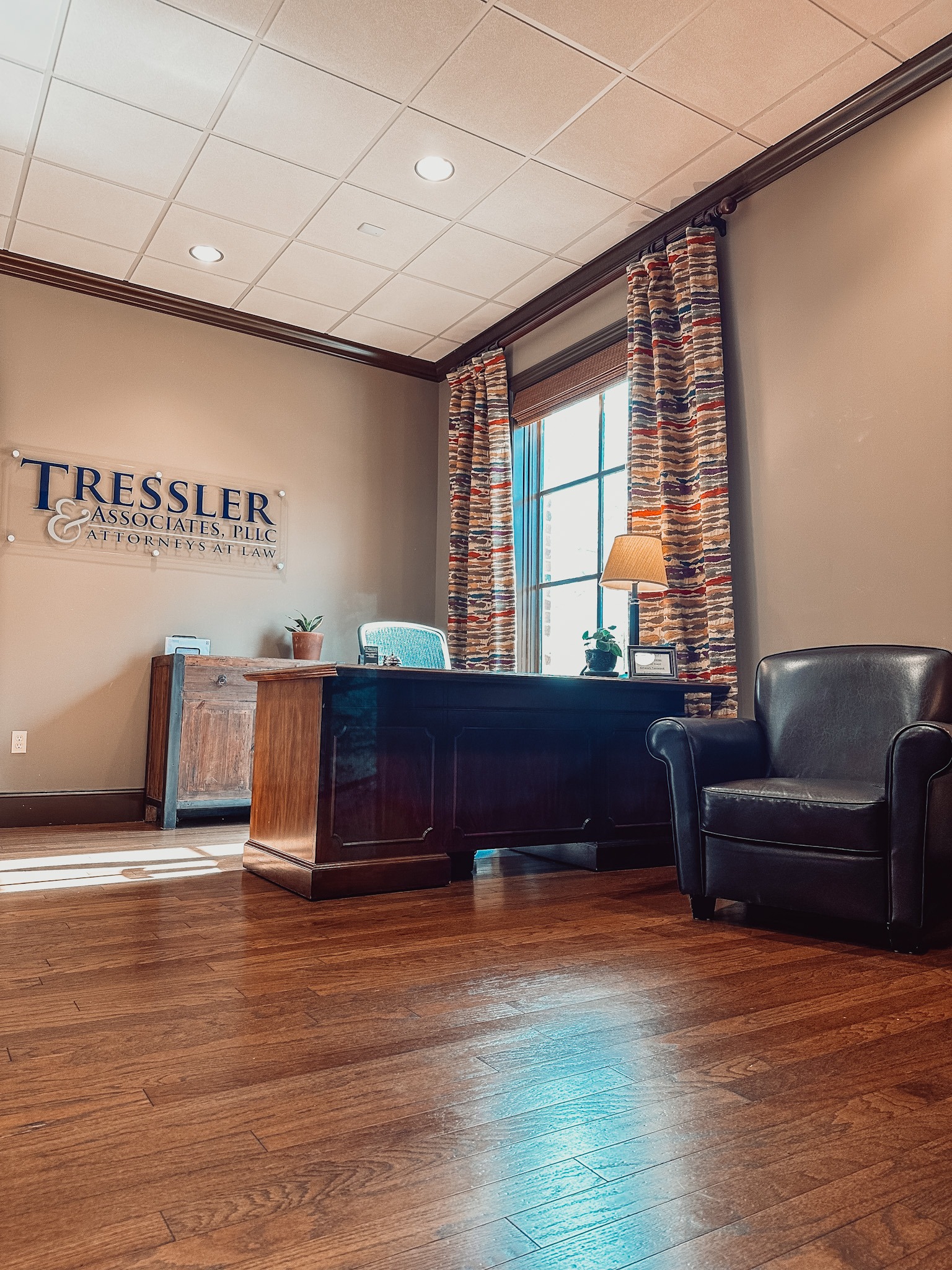 Tressler & Associates, PLLC Lebanon Office front lobby picturing wood floors, wooden desk and leather chair with sunlight coming through window