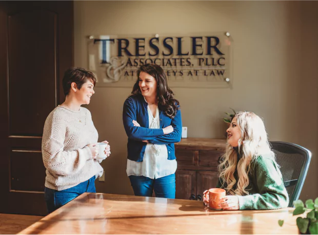 Left to right: Megan Climer, Christen Rabe, Mykela Lesso talking together in the front lobby of the Tressler office